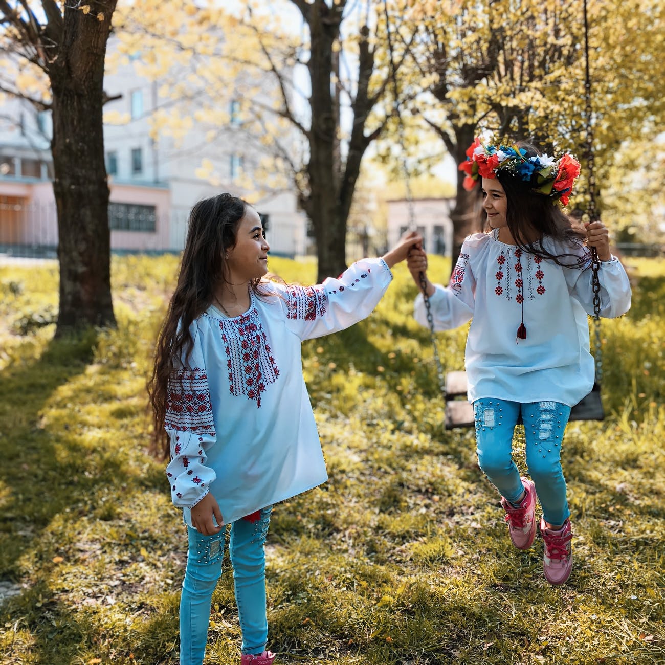 little girls playing outside on a swing