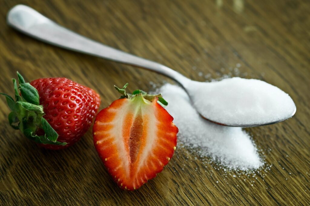 strawberry beside spoon of sugar