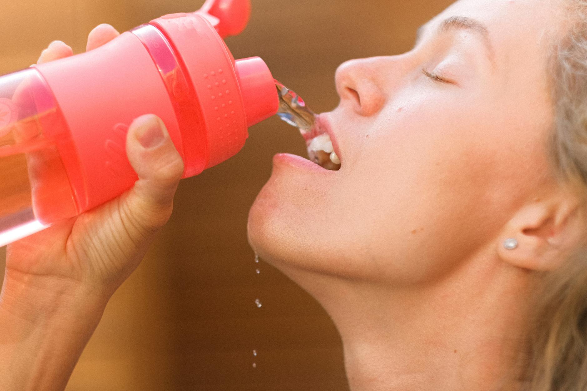 crop thirsty sportswoman drinking water from bottle