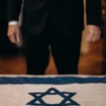 man standing next to the flag of israel