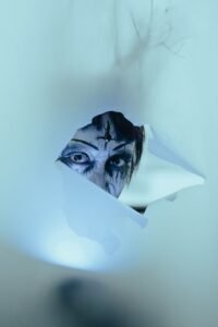 person in halloween makeup looking through a hole in fabric