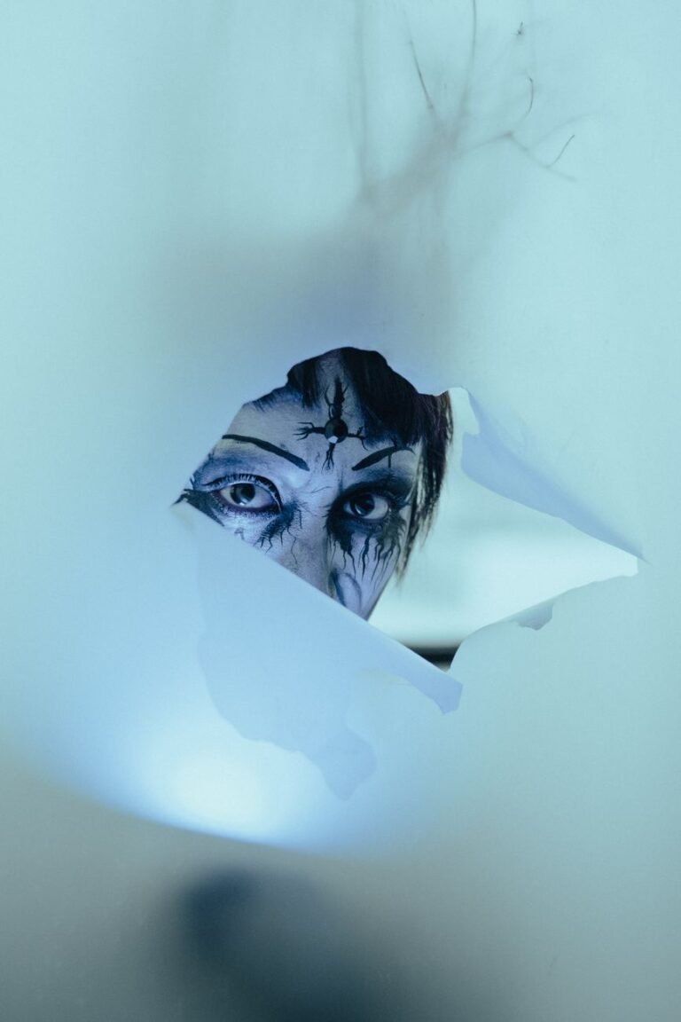 person in halloween makeup looking through a hole in fabric