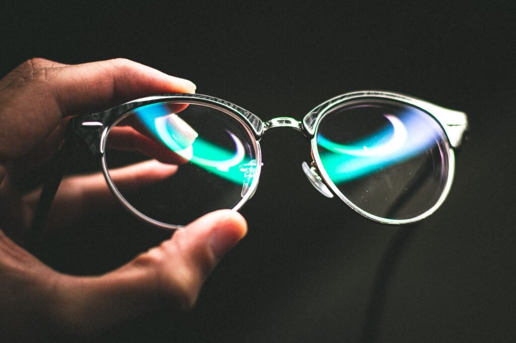 faceless person holding trendy glasses against black background