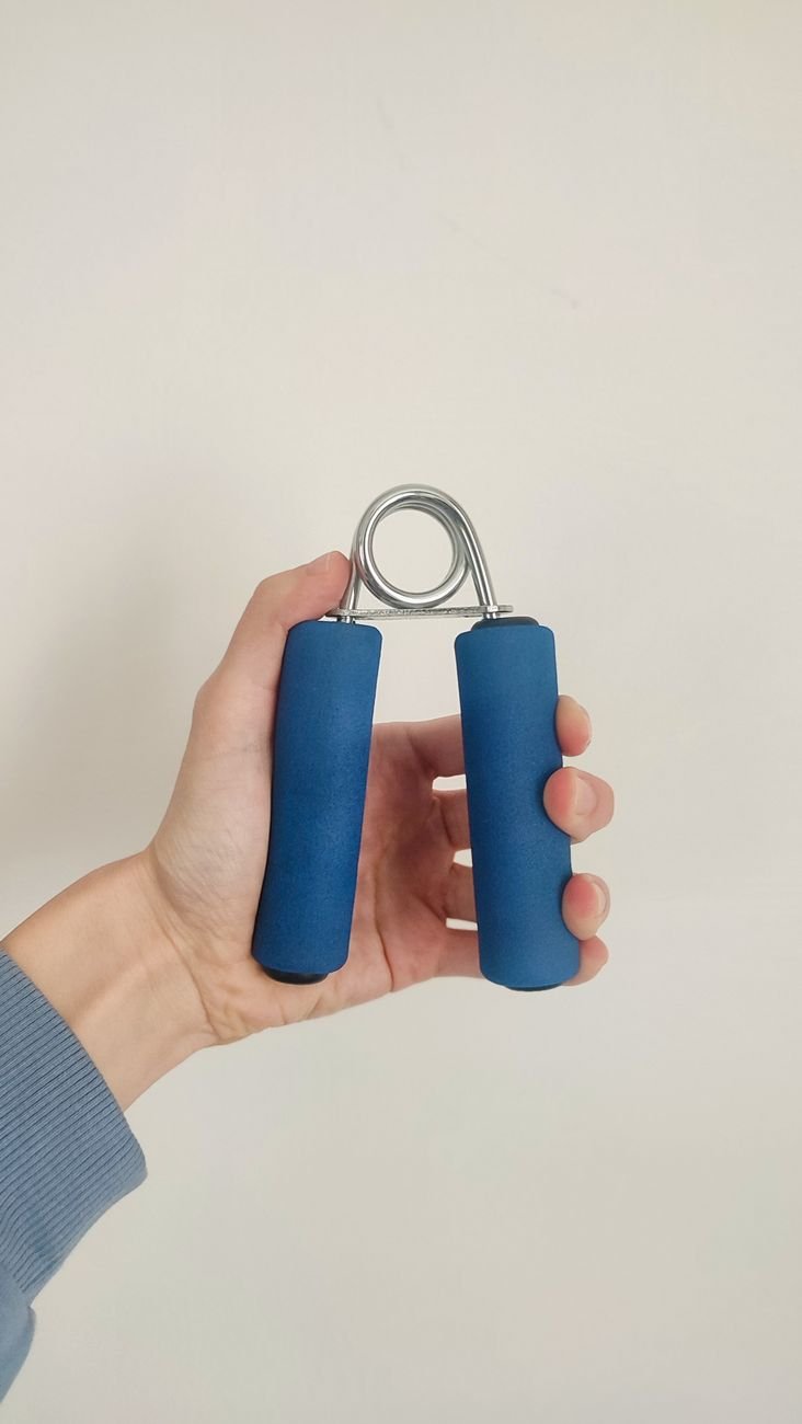 hand holding blue grip strength exercise tool