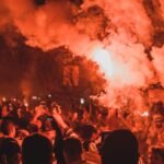 anonymous people standing on street among smoke during protests at night